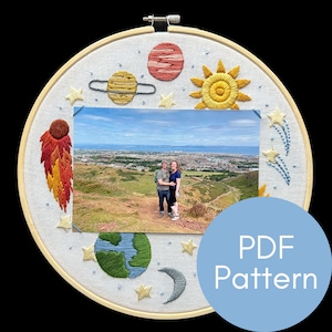 May include: A white embroidery hoop with a colorful embroidered design of planets, stars, and a comet. A photo of a couple is in the center of the hoop. The text "PDF Pattern" is on a blue circle in the lower right corner of the image.