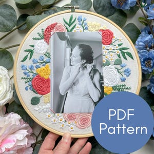 Puede incluir: Un bastidor de bordado con una foto en blanco y negro rodeada de bordados florales coloridos. El bastidor está adornado con flores rojas, rosas, amarillas y azules. Un círculo azul con el texto "PDF Pattern" es visible.