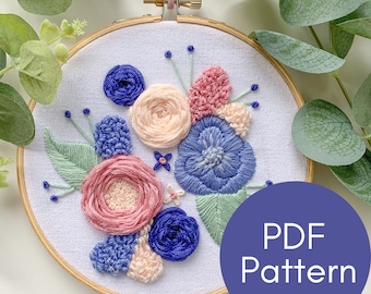 Puede incluir: Diseño floral bordado en un aro de madera. La obra de arte presenta un ramo de flores rosas, azules y melocotón con hojas verdes. El texto "PDF Pattern" está en un círculo morado.