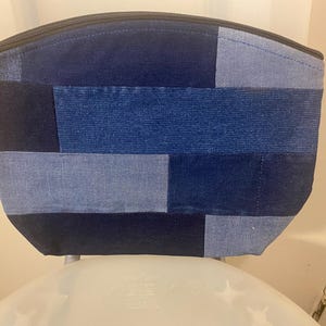 May include: A blue denim patchwork makeup bag with a zipper closure.