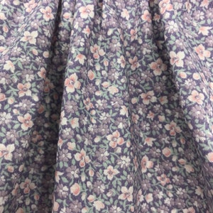 May include: Close-up of a purple fabric with a small white and pink floral pattern.