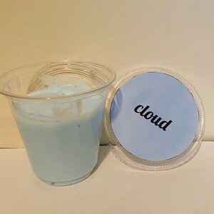 以下が含まれることがあります： 透明なプラスチックカップに、白い泡のトップが付いた薄い青色のスライムが入っています。スライムには、別の透明なプラスチック製の蓋に「cloud」とラベルが貼られています。