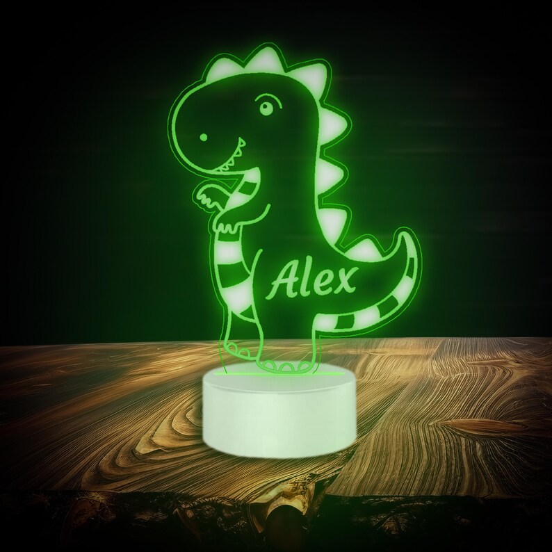 May include: Green dinosaur night light with the name "Alex" on the body. The light is on a white base.