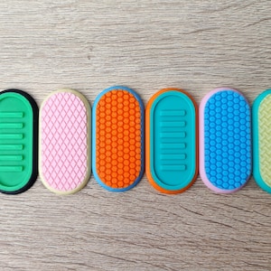 May include: Six oval-shaped silicone tools with different textures and colours. The tools are green, pink, orange, blue, light blue, and yellow.