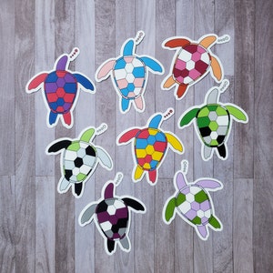 May include: Eight colorful turtle stickers with geometric patterns. Each turtle has a different color scheme and pattern, including red, blue, green, yellow, black, and white.