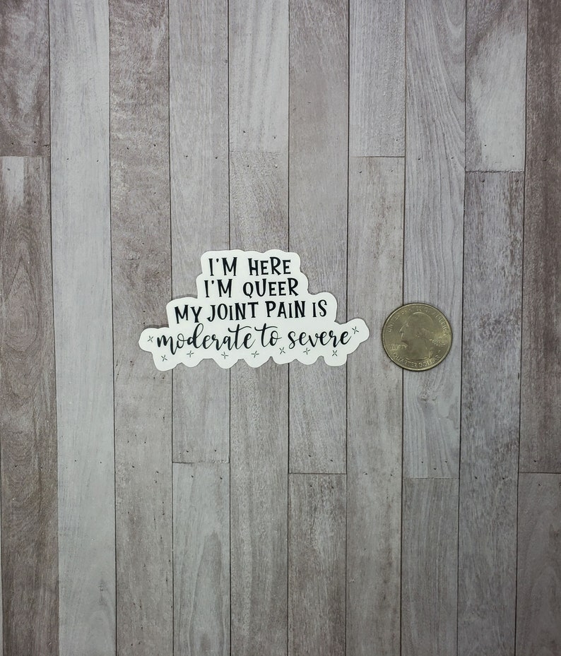 May include: White sticker with black text that reads "I'm here I'm queer My joint pain is moderate to severe".