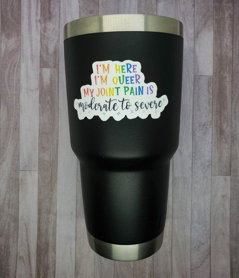 May include: Black stainless steel tumbler with a rainbow sticker that reads "I'm here I'm queer My joint pain is moderate to severe".