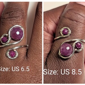 Op de afbeelding: Een zilverkleurige draadring met drie gefacetteerde, dieproze edelstenen. De ring heeft een spiraalvormig ontwerp met een grotere centrale steen en twee kleinere accentstenen. De tekst "Size: US 6.5" en "Size: US 8.5" is zichtbaar.