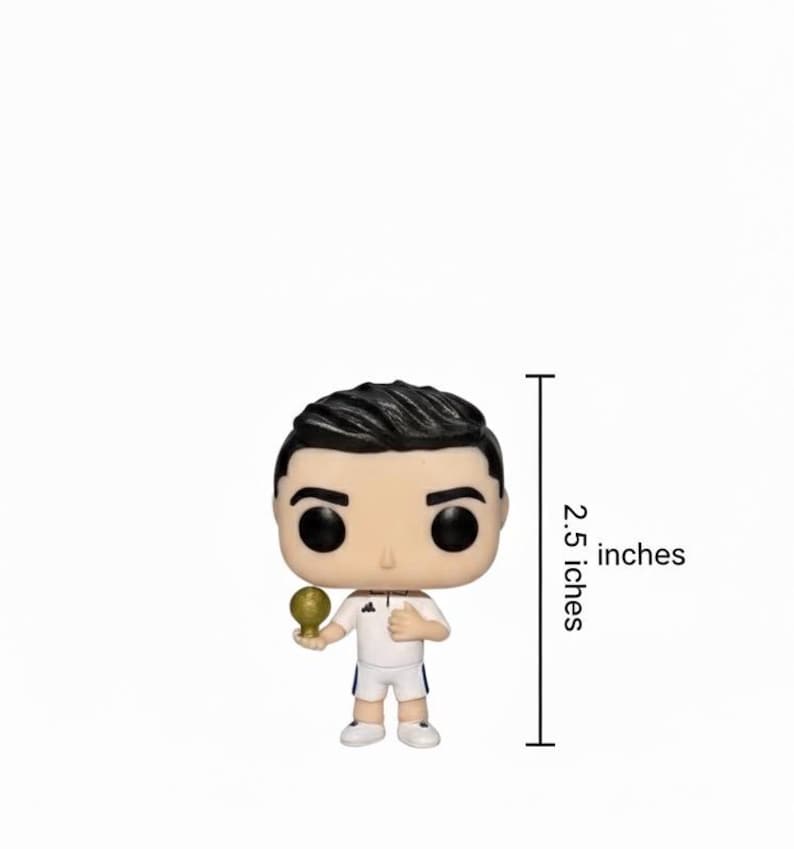 May include: A Funko Pop vinyl figure of a footballer, 6.35 cm tall, in a white uniform. The figure has black hair and large black eyes, and is holding a golden trophy.