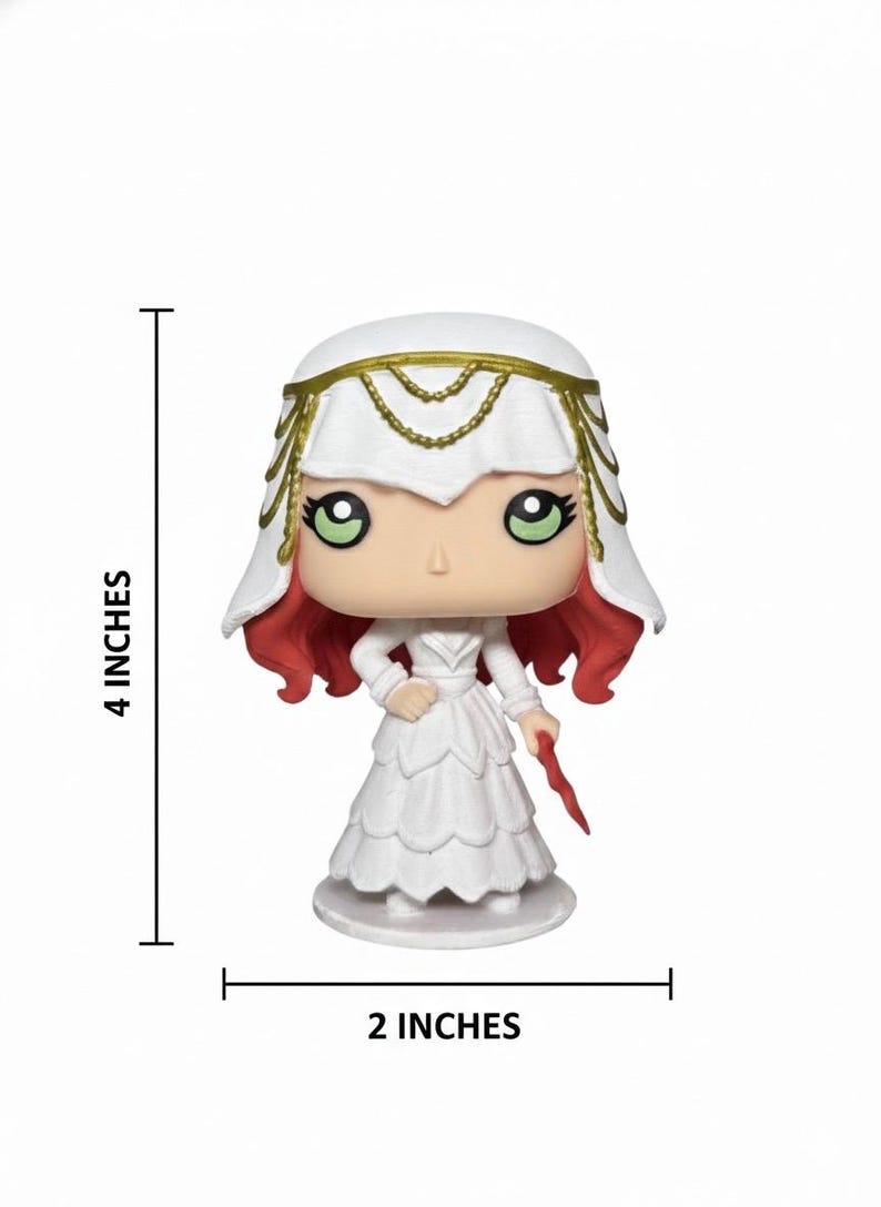 May include: A white figurine of a woman in a long dress, 4 inches tall and 2 inches wide. She has red hair, green eyes, and a white veil with gold accents. She holds a red object in her right hand. The figurine is on a white base.