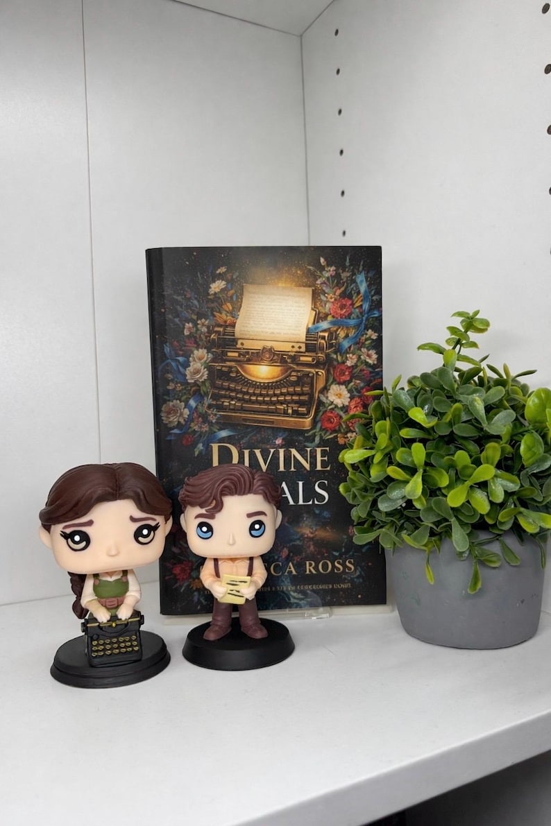 以下が含まれることがあります： 2体のFunko Popフィギュア、本、鉢植えの植物が置かれた棚。本の表紙には「Divine ALS」と書かれ、ヴィンテージのタイプライターのイラストが描かれています。フィギュアは男性と女性です。植物は灰色の鉢に入っています。