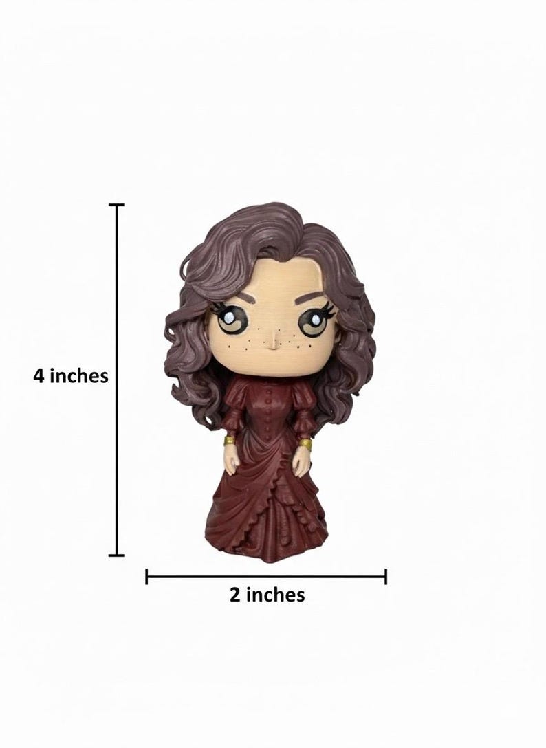 Może przedstawiać: Figurka kobiety z brązowymi kręconymi włosami i bordową sukienką. Figurka ma około 10 cm wysokości i 5 cm szerokości. Kobieta ma duże oczy i piegi. Złote akcenty na rękawach. Figurka na białym tle.