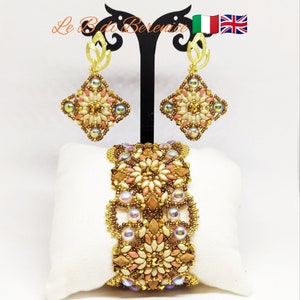 May include: A set of beaded jewelry featuring a bracelet and earrings. The bracelet and earrings are made with beige, brown, and gold beads. The earrings are teardrop shaped and dangle from a gold hook.