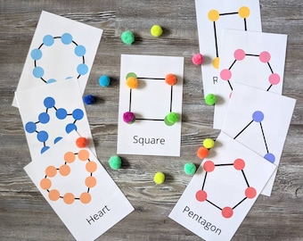 May include: A set of colorful cards with different geometric shapes, including a circle, square, heart, pentagon, and star. Each card has a name and a dotted outline of the shape. There are also colorful pom-poms scattered around the cards.