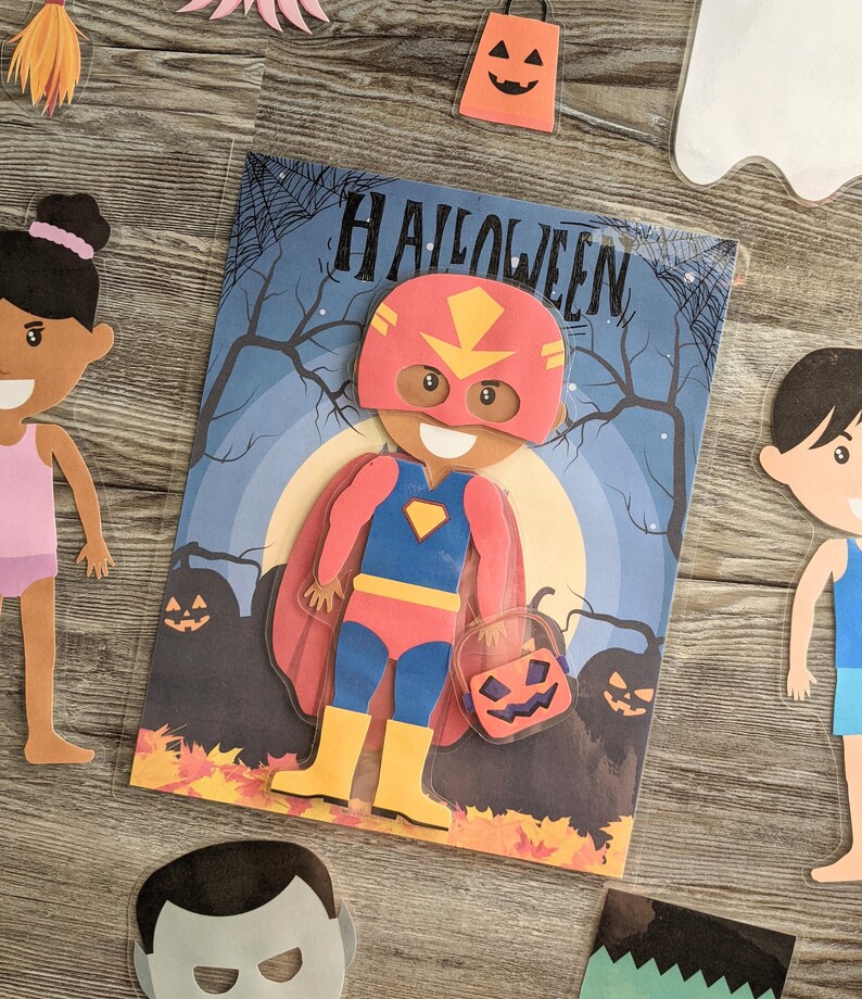May include: A Halloween-themed paper craft set with a red, blue, and yellow superhero character holding a jack-o'-lantern. The set also includes a girl with brown hair, a boy with brown hair, and a ghost.