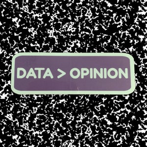 Könnte beinhalten: Ein violetter Aufkleber mit abgerundeten Ecken und einem weißen Rand. Der Aufkleber sagt "DATA > OPINION" in weißer Schrift.
