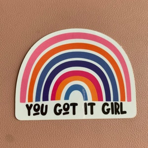 May include: A rainbow sticker with the text "You Got It Girl" in black lettering.
