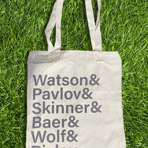 May include: A white canvas tote bag with black text that reads "Watson & Pavlov & Skinner & Baer & Wolf & Risley."