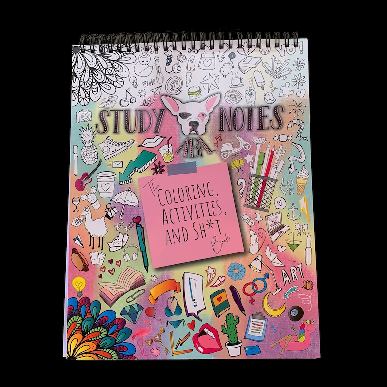 Op de afbeelding: Een roze en wit spiraalnotitieblok met een kleurrijk doodle-ontwerp. De omslag heeft een cartoonhond, verschillende objecten en de tekst "STUDY NOTES The COLORING, ACTIVITIES, AND SH*T Book".