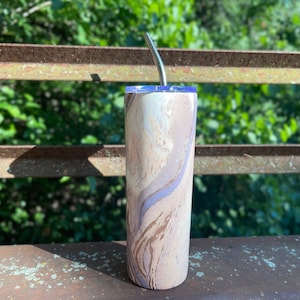May include: A stainless steel tumbler with a marbleized design in shades of white, brown, and purple. The tumbler has a lid and a straw.