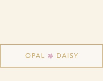 Op de afbeelding: Een witte rechthoek met een gouden rand en de tekst "OPAL * DAISY" in zwart.