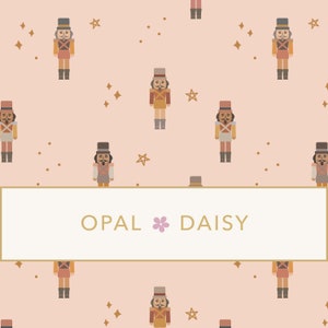 May include: A seamless pattern featuring a repeating design of nutcracker soldiers with brown hats and red and brown uniforms, gold stars, and small brown dots on a light pink background. The text "OPAL DAISY" is centered in a white rectangle with a gold border.