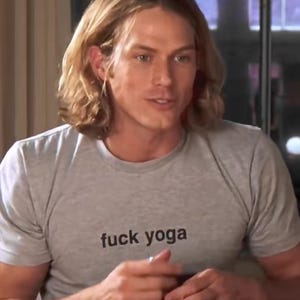 May include: A light gray short-sleeved t-shirt featuring the text "fuck yoga" printed in black lowercase letters across the chest. The garment has a crew neckline and a standard fit, constructed from a soft, heathered cotton-blend fabric.