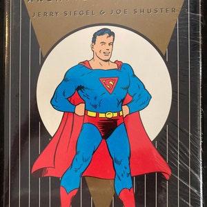 May include: A book cover featuring a comic book illustration of Superman in his iconic red and blue suit, standing with his hands on his hips. The cover text reads "Superman Archives Volume 2 Jerry Siegel & Joe Shuster".