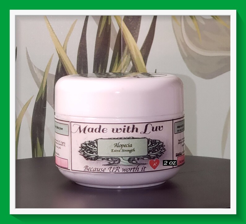 Puede incluir: Un tarro rosa con una etiqueta blanca que dice "Made with Luv Alopecia Extra Strength Because UR worth it" y un coraz&oacute;n rojo. El tarro contiene 2 oz de producto.