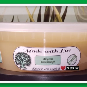 Puede incluir: Un recipiente de pl&aacute;stico blanco con un l&iacute;quido de color amarillo en su interior. El recipiente tiene una etiqueta que dice "Made with Luv", "Alopecia Extra Strength", "Because UR worth it", y "8.50 oz". La etiqueta tambi&eacute;n tiene un &aacute;rbol verde y un coraz&oacute;n rojo.
