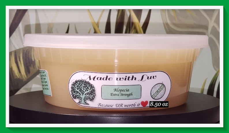 Puede incluir: Un recipiente de pl&aacute;stico blanco con un l&iacute;quido de color amarillo en su interior. El recipiente tiene una etiqueta que dice "Made with Luv", "Alopecia Extra Strength", "Because UR worth it", y "8.50 oz". La etiqueta tambi&eacute;n tiene un &aacute;rbol verde y un coraz&oacute;n rojo.