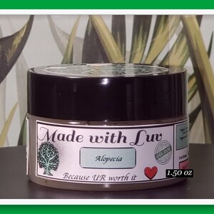 Puede incluir: Un peque&ntilde;o tarro marr&oacute;n con tapa negra. La etiqueta dice "Made with Luv" con un logotipo de &aacute;rbol, "Alopecia", "Because U'R worth it" y un coraz&oacute;n rojo. El tarro tambi&eacute;n tiene una etiqueta "Organic" y dice "1.50 oz".
