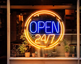 May include: A neon sign with an orange circle and blue text that reads "OPEN 24/7". The sign is in a storefront window with plants in pots in front of it.