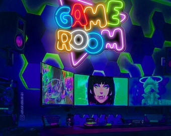 Puede incluir: Un letrero de neón que dice "GAME ROOM" en una habitación oscura con una configuración de juego. El letrero está hecho de luces de neón de colores y está montado en una pared con un patrón de panal. La configuración de juego incluye tres monitores, un teclado y un ratón.