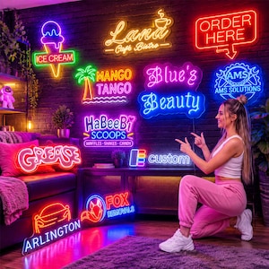 May include: A collection of various neon signs mounted on a dark brick wall, featuring text and graphics including an ice cream cone, a palm tree, the words Lana Cafe Bistro, Order Here, Blue's Beauty, HaBeeBi Scoops, Grease, and Fox Removals.