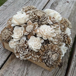May include: A wooden box filled with a variety of cream and brown sola wood flowers. The flowers are arranged in a circular pattern and are all different sizes and shapes.