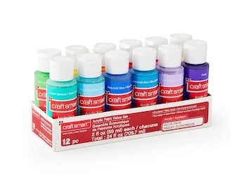 Puede incluir: Un juego de 12 botellas de pintura acrílica craft smart en una variedad de colores, incluyendo verde, azul, morado y amarillo. Las botellas son de 2 onzas líquidas cada una y están dispuestas en una caja con el texto "craft smart Acrylic Paint Value Set" en la parte delantera.
