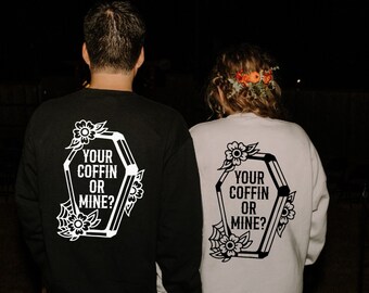 May include: A couple wearing matching black and white sweatshirts with a coffin graphic and the text "Your Coffin or Mine?" printed on the back.