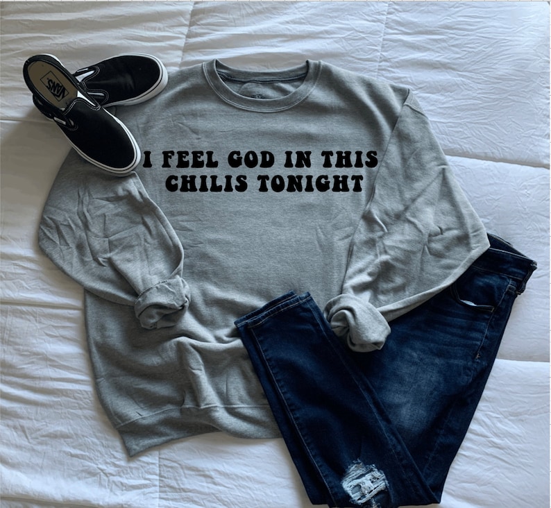 May include: Gray sweatshirt with the text "I feel god in this chilis tonight" in black retro font.