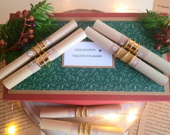 May include: A set of brown paper scrolls with gold rings and numbers on them. The scrolls are arranged in a semi-circle on a red and green box. The box has a white label that says "Geschichten * Adventskalender".