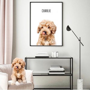 May include: A digital illustration of a dog named Charlie. The dog is a light brown color with a fluffy coat and is looking directly at the viewer. The illustration is framed in a black frame and is hanging on a white wall.
