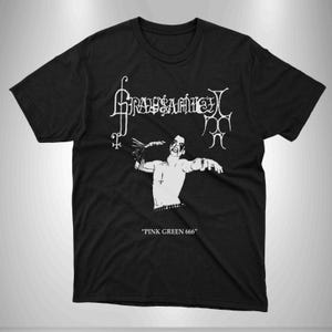 Può includere: Maglietta nera con una stampa grafica bianca di una band chiamata "Grausamkeit" con una persona che tiene un coltello e il testo "Pink Green 666".