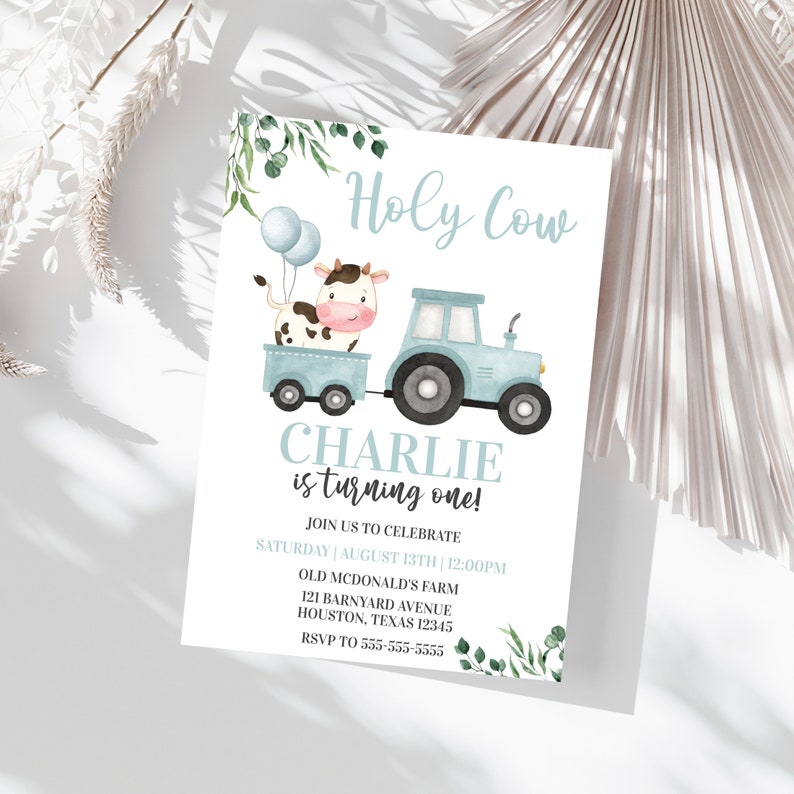 Puede incluir: Una invitaci&oacute;n de cumplea&ntilde;os azul y blanca con una vaca y un tractor de dibujos animados. El texto dice "Holy Cow Charlie is turning one!" con detalles para la fiesta.