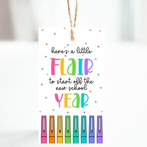 May include: A white gift tag with the text "here's a little FLAIR to start off the new school YEAR" in colorful letters. The tag is decorated with colorful dots and a row of colorful pens.