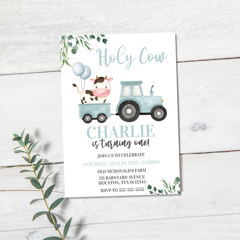 Puede incluir: Una invitaci&oacute;n de cumplea&ntilde;os azul y blanca con una vaca de dibujos animados que viaja en un tractor de juguete azul. La invitaci&oacute;n dice "Holy Cow Charlie cumple un a&ntilde;o!" e incluye detalles para la fiesta, como la fecha, la hora, la ubicaci&oacute;n y la informaci&oacute;n de RSVP.
