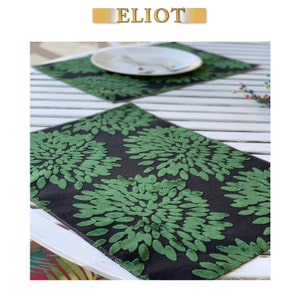 May include: Green and black placemats with a floral pattern. The placemats are made of a soft, textured fabric.