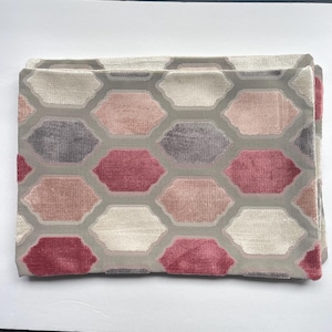 May include: Two decorative throw pillows with a geometric pattern in shades of pink, gray, and white.