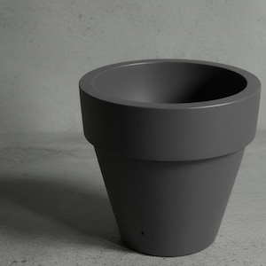 May include: A dark gray, smooth-surfaced, tapered plant pot with a wide, thick rim. The container features a conical shape that narrows toward the base, which includes a single small drainage hole visible near the bottom edge.