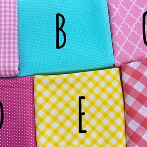 May include: Six fabric swatches in different patterns and colors.  A is pink and white gingham, B is light blue with white dots, C is pink with a white geometric pattern, D is pink with white dots, E is yellow with white gingham, and F is pink and white gingham.