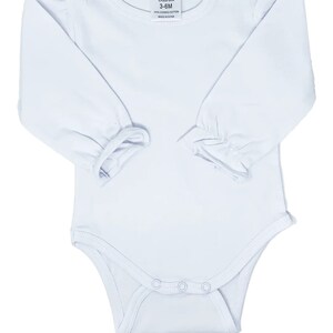 May include: White long-sleeve baby onesie with ruffled sleeves and snap closures. The onesie has a label that reads "AJ Blanks 3-6M 100% Combed Cotton Made in China."